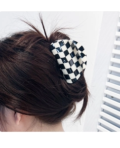 Macro view of large black and white checkerboard claw clip on dark hair for hair styling