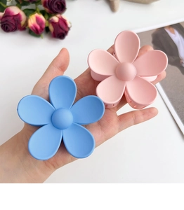 Detail showing large matte floral hair claws in light blue and pink for elegant hair styling