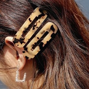 Tortoise shell acetate hair clip and sparkly rhinestone earrings on a woman's hair