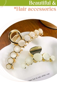 Macro shot of two vintage gold metal hair claws set with round white opal stones