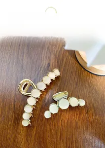 Detailed view of gold metal hair claws with opal stones on a dark wooden surface