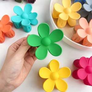 Matte macaron flower hair claws in multiple colors shown on a minimalist wooden plate