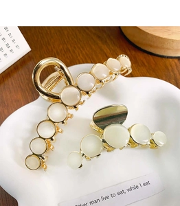 Golden opal claw hair clips in two sizes displayed on a white cloud ceramic tray