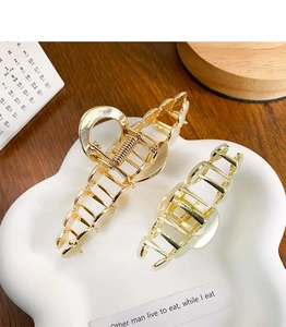 Detail view of two gold cat-eye metal hair claws with elegant heart cutout design