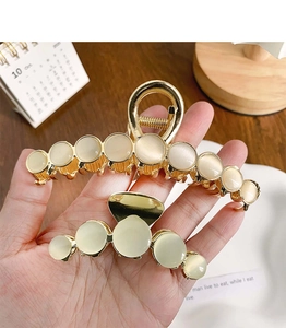 Detailed close-up of golden metal hair claws with cat-eye stones in large and small sizes