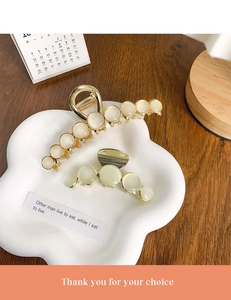 Detail of two golden cat eye stone hair claws on a decorative white porcelain tray