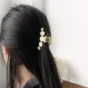 Golden metal hair claw with five gradient white beads shown on dark hair back view