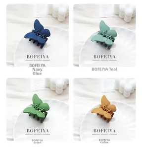 Détail de quatre pinces à cheveux papillon mates en bleu marine, cyan, vert et marron