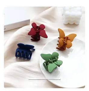 Pinces à cheveux papillon mates en quatre couleurs présentées sur de la soie et une assiette