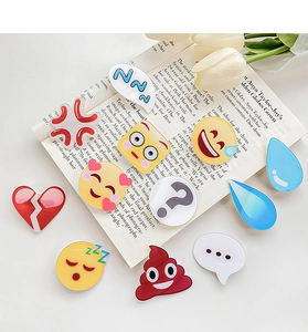 Detailaufnahme kreativer Emoji-Acryl-Haarspangen auf Modemagazin mit weißen Tulpen