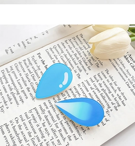 Nahaufnahme blauer Wassertropfen-Haarspangen auf Magazin mit weißen Tulpen