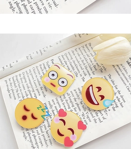 Detailansicht von vier lustigen Emoji-Ansteckern mit Glanzfinish auf Magazin-Hintergrund