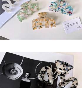 Detailed view of M-shaped acetate hair claws in various marble and floral patterns