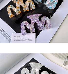 Close-up of multicolored marble pattern acetate hair claws on a fashion magazine