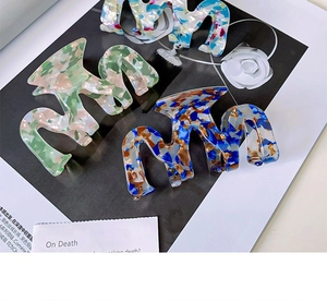 Detailed close-up of wavy acetate hair claws in marble, tortoiseshell and floral patterns