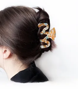 Detail of wavy acetate hair claw clip with amber marble texture on a model's hair