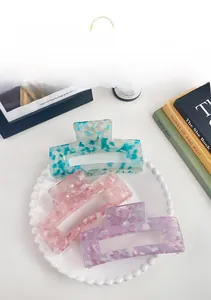 Three large matte acetate hair claws in pastel marble patterns on a white tray