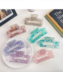 Flat lay of six colorful 13cm acetate rectangle hair claws with trendy marble patterns
