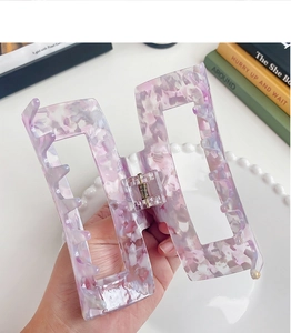 Detail of a rectangle cutout marbled acetate hair claw clip in purple and pink tones