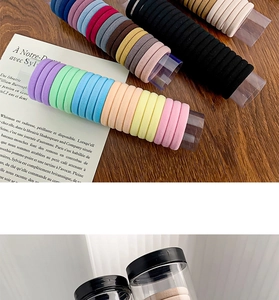 Close-up of assorted colorful high-elastic hair ties on a clear cylindrical storage tube