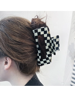 Large black and white checkerboard hair claw clip securely holding thick hair in a side view