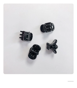 Détail de quatre mini pinces à cheveux noires brillantes avec ressorts en métal
