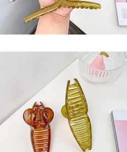 Detail of 13cm oversized hair claw clips in olive green and amber translucent colors