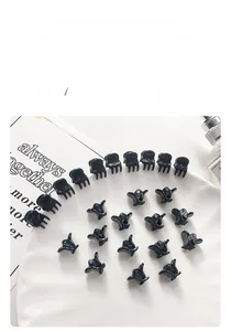 Lot de mini pinces à cheveux noires pour coiffage sur un plateau décoratif blanc