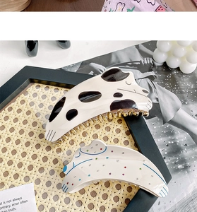 Détail de pinces à cheveux chiot avec motif dalmatien et pois colorés sur un plateau noir