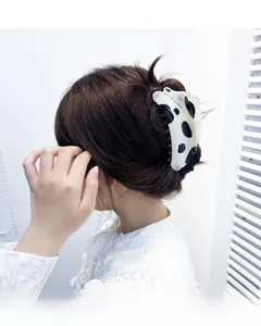 Détail d'une grande pince à cheveux en acétate à motif vache portée en chignon