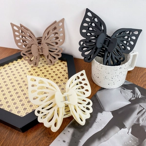 Matte Schmetterlings-Haarklammern in Schwarz, Braun und Creme auf einer Holzoberfläche