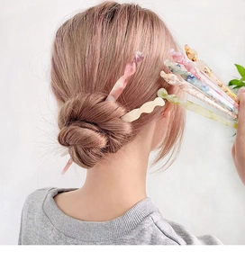 Detail showing wavy acetate hair pins in various marbled colors used for a modern bun hairstyle