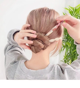 Detail of pink marble pattern and cream wave acetate hair sticks in a bun hairstyle
