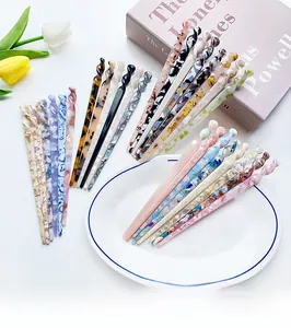Close-up of spiral acetate hair pins in various patterns on a minimalist white tray