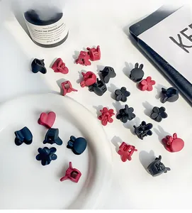 Detailed flat lay of mini matte flower and rabbit hair clips in dark red and black colors