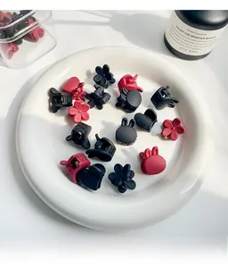 Detailed macro view of mini matte hair claws in floral and heart shapes on a ceramic plate