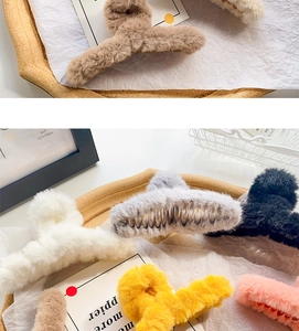 Macro detail of plush faux fur hair claw clips in various winter colors on decorative tray