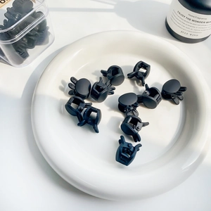 Matte black mini rabbit ear hair claws set for children shown on a white ceramic plate