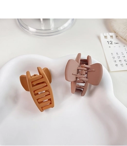 Detail of matte hair claws in caramel and dusty pink with hollow butterfly wing design