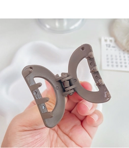 Detail view of matte brown hair claw clip with metal spring and hollow structure