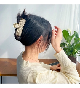 Detail view of large pearl-encrusted alloy hair claw clip on model in retro hair style