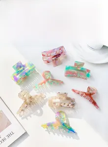 Flat lay of acetate claw clips in marble and floral patterns with natural shadows
