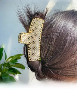 Detailed view of a gold-toned large claw clip with rhinestones in hair