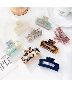 Set of eight elegant acetate hair claws in various marble and jelly colors on a white desk