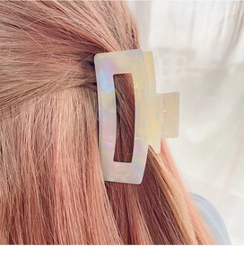 Detail of square cutout acetic hair claw clip showing iridescent opal pearl texture on hair
