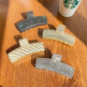 Retro rhinestone large hair claws in silver, gold, and grey colors on a wooden table