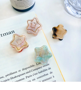Detail of four acetate starfish hair clips with smiling face on an open book