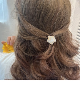 Close-up of star-shaped acetate hair clip on wavy brown hair showing detailed texture