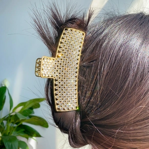 Elegant large gold hair claw clip with full rhinestones on dark braided hair