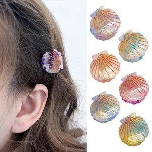 Macaron shell-shaped acetate hair clips with pearl luster and golden linear details